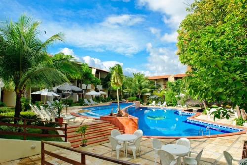 a pool at a resort with white chairs and trees at Solar Pipa Apartamentos in Pipa