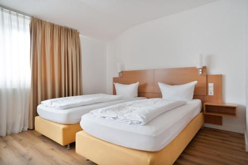 two beds in a hotel room with white sheets at Schöne Apartments I Kostenloses Parken I home2share in Münster