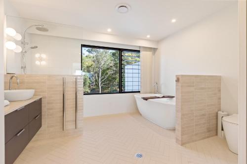 a bathroom with a tub and a sink and a toilet at Perfectly Pambula in Pambula Beach