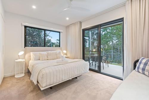 a bedroom with a bed and a large window at Perfectly Pambula in Pambula Beach
