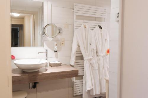 een witte badkamer met een wastafel en een spiegel bij Hotel De Hofkamers in Oostende