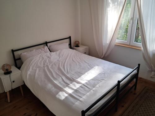 a bedroom with a bed with white sheets and a window at Leśne Zacisze in Wijewo