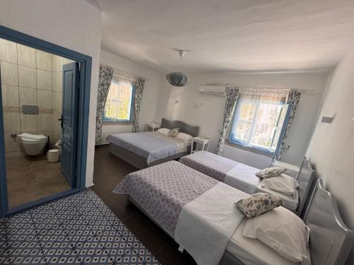 a bedroom with two beds and a bathroom at Çakir Bey Hotel in Alaçatı