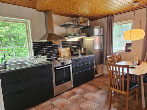 eine Küche mit Herd, Spüle und Tisch in der Unterkunft Sniberup in Hörby