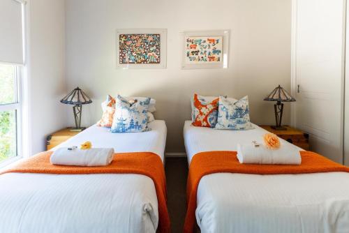 two beds in a room with orange and blue pillows at Hunter Moon in Broke