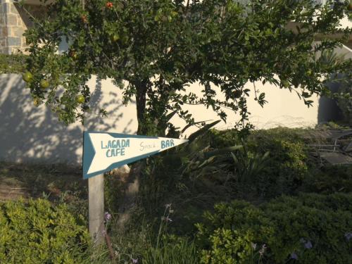 un cartello stradale blu e bianco davanti a un albero di Lagada Resort a Makris Gialos