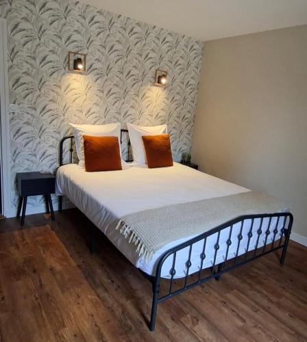 a bedroom with a bed with white sheets and orange pillows at B&B Le Chardon in Saint-Gervais-les-Trois-Clochers