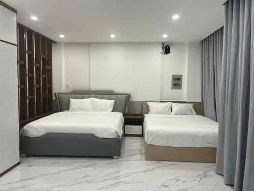 two beds in a hotel room with white sheets at Cozy Corner Beach Hotel in Phú Quốc