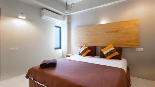a bedroom with a large bed with a wooden headboard at Madivaru Kro in Rasdhoo