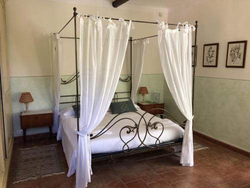 a bedroom with a canopy bed with white curtains at Cascina Bolichin in Diano dʼAlba