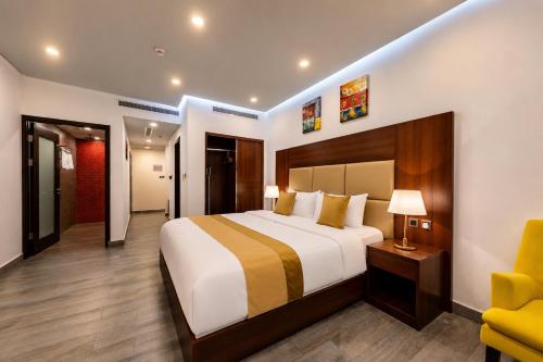 a bedroom with a large bed and a yellow chair at Rosalina Hotel in Yanbu