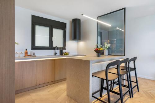 a kitchen with a counter with stools and a sink at Urban Heights Ammoudi Seafront in Agios Nikolaos