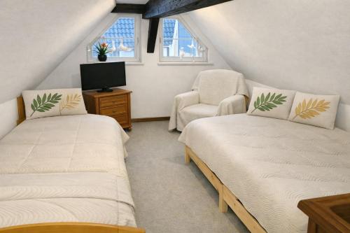 a attic room with two beds and a chair at Fachwerkhaus Bodenwerder in Bodenwerder