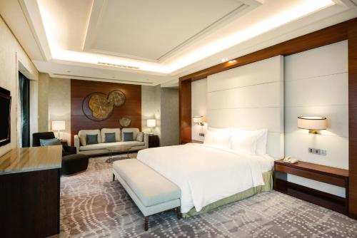 a bedroom with a white bed and a living room at Holiday Inn Chengdu Xindu by IHG in Chengdu