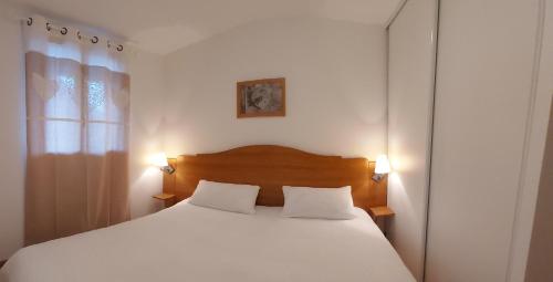 a bedroom with a white bed with two pillows at Bel appartement montagne in Albiez-Montrond