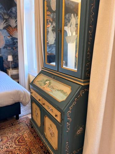 a green cabinet with a painting on it next to a bed at Le Palais d'Orient - Suite avec salle d'eau in Hannut