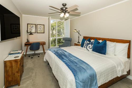a bedroom with a bed with a ceiling fan and a desk at B205 - Ocean Escape in Oceanside