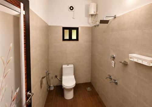 a small bathroom with a toilet and a window at Sheen Villa Homestay in Varkala