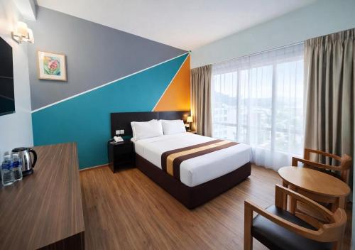 a hotel room with a large bed and a table at Alami Garden Hotel in Shah Alam