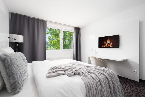 a white bedroom with a bed and a fireplace at MICE Collection Hotel Trier Business- und Stadthotel an der Mosel nahe SWT Arena und Viking Anleger in Trier