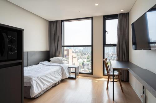 a bedroom with a bed and a desk and windows at Celib Yeoui in Seoul