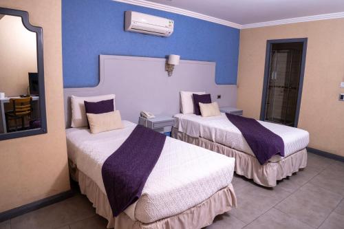 a hotel room with two beds and a mirror at Infinity Park Hotel in Santiago