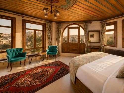 a bedroom with a bed and chairs and windows at Premium Cappadocia in Göreme