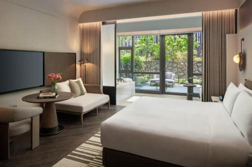 a hotel room with a bed and a living room at Kimpton Nine Trees Shanghai by IHG in Shanghai