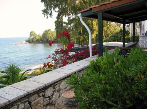 a retaining wall with flowers and a view of the water at Grekis Beach Hotel and Apartments in Petalidhion