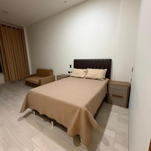 a bedroom with a large bed and a chair at Plaza Central Boutique House in Cochabamba