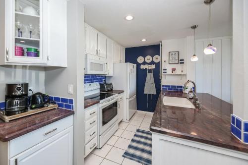 a kitchen with white cabinets and a sink and a refrigerator at D4 - Lighthouse on the Shore in Oceanside