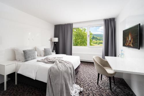 a hotel room with a bed and a desk and a window at MICE Collection Hotel Trier Business- und Stadthotel an der Mosel nahe SWT Arena und Viking Anleger in Trier