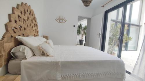 a white bedroom with a large bed and a window at LA MAISON DE MARIE A 8 mn des plages in Perpignan