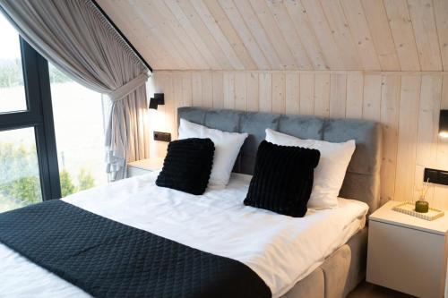 a bedroom with a bed with black and white pillows at Craftowe domki in Rusinowo