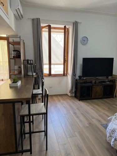a living room with a television and a table and chairs at Sa Domitta due Alghero in Alghero