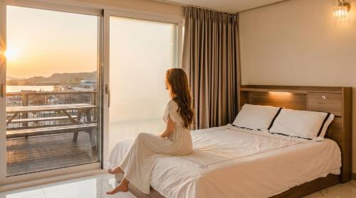 a woman sitting on a bed in a hotel room at Ganghwa Glory Bada Pension in Incheon