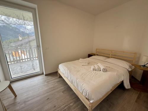 ein Schlafzimmer mit einem Bett und einem großen Fenster in der Unterkunft Feder Peaks in Canale dʼAgordo