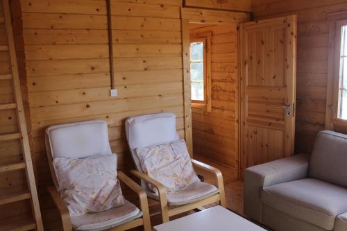 two chairs and a couch in a room with wooden walls at Finca el enebro in Valdemorillo