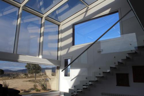 a glass house with stairs and a large window at Finca el enebro in Valdemorillo