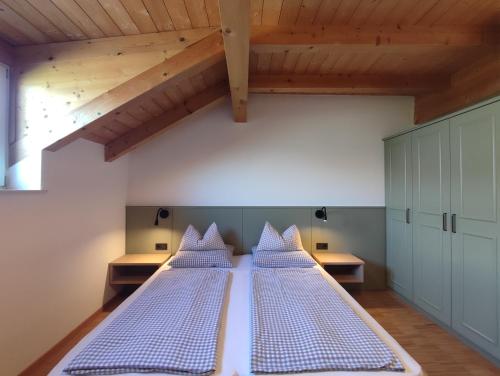 two beds in a room with wooden ceilings at Residence Hof am Keller in Montagna