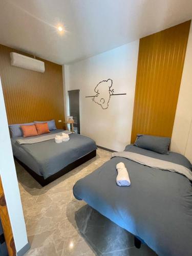 a bedroom with two beds and a bear sticker on the wall at V house 1 in Ban Huai Yai