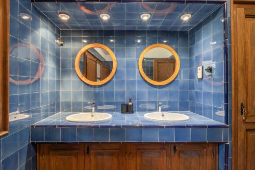 a blue tiled bathroom with two sinks and two mirrors at Apartamento I Els Cucons in Sant Pere de Ribes