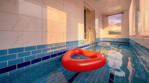 a swimming pool with a red seat in the water at Gapyeong Ribbon Spa Pool Villa in Gapyeong