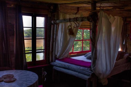 a bedroom with two windows with a bed and a table at Cabane Layénie sous les étoiles in Bajamont