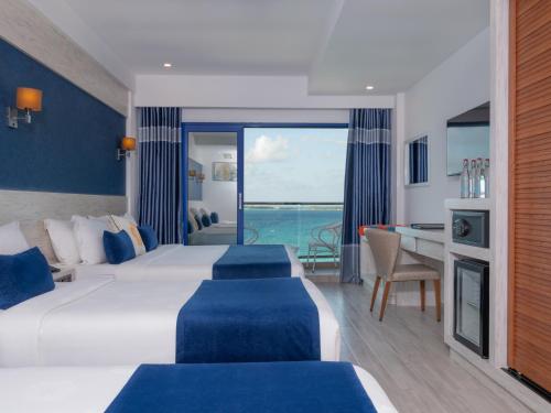 a hotel room with two beds and a view of the ocean at Kaani Palm Beach in Maafushi