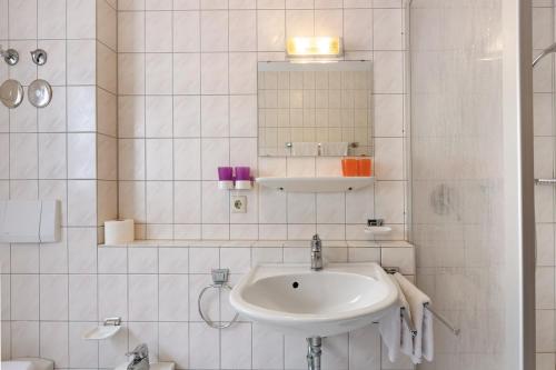 a white bathroom with a sink and a mirror at Apartment 30 in Bad Dürrheim