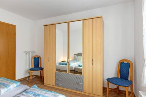 a bedroom with a wooden cabinet and two blue chairs at Apartment 47 in Bad Dürrheim