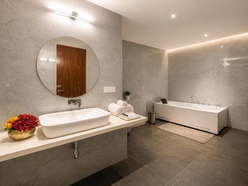 a bathroom with a sink and a tub and a mirror at VITS Satyajeet Karad in Karād