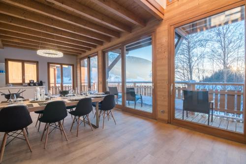 a dining room with a table and chairs and large windows at Les Portes de Megève in Praz-sur-Arly
