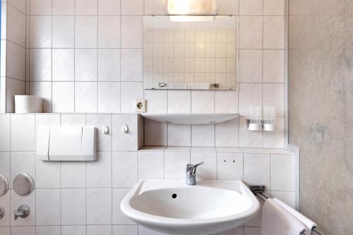 a white bathroom with a sink and a mirror at Apartment 36 in Bad Dürrheim